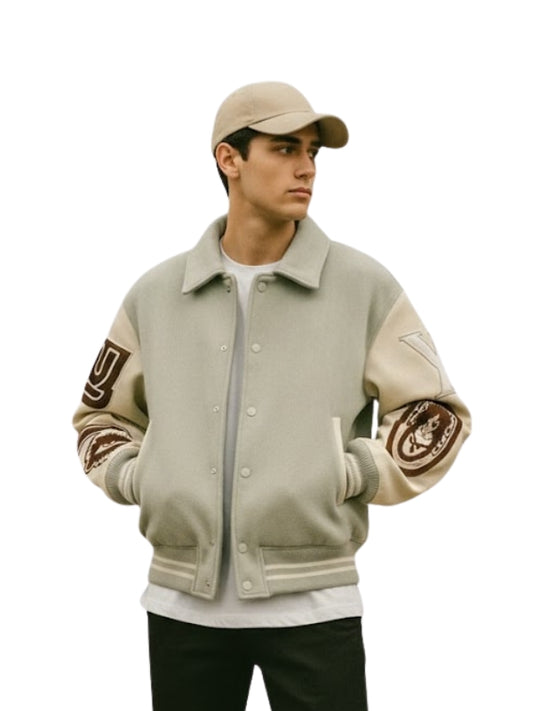 Person wearing a beige varsity jacket with arm patches on a white background