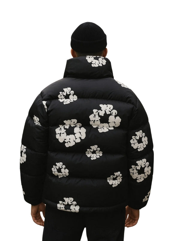 Black puffer jacket with white floral patterns worn by a person on a white background