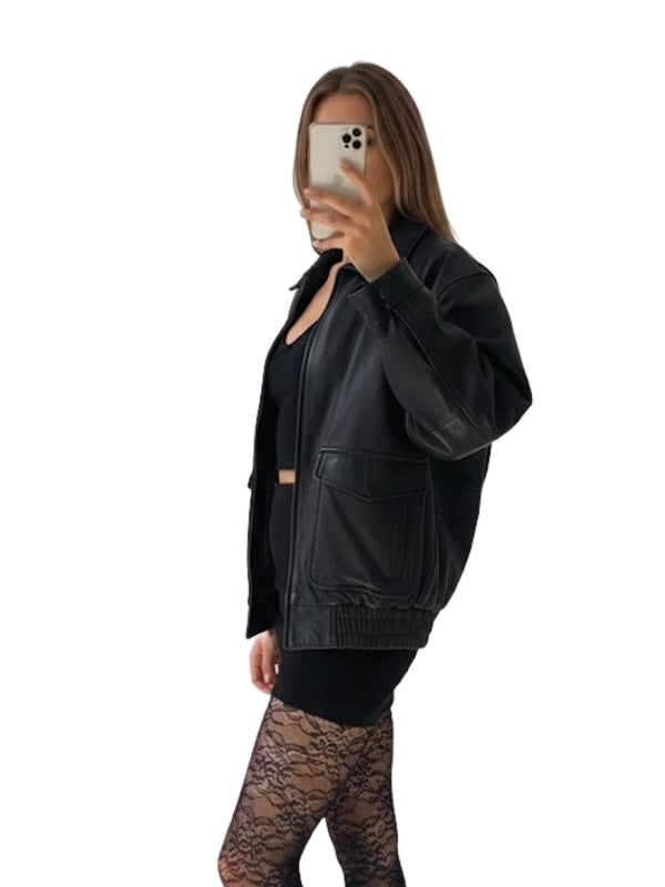 Person wearing a black leather jacket and black leggings on a white background