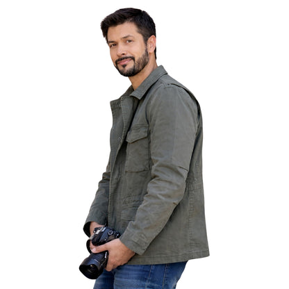 Man wearing a gray jacket holding a camera on a white background