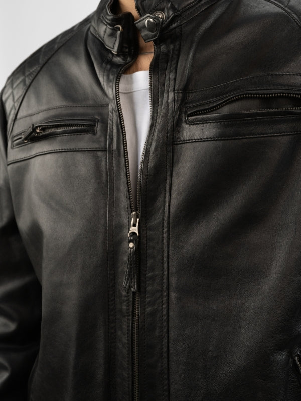 Close-up of a black leather jacket with zippers on a plain background