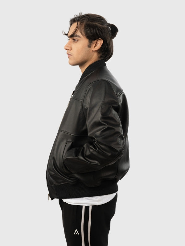 Person wearing a black leather jacket and black pants with white stripes on a light gray background