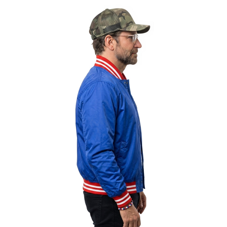 Man wearing a blue jacket with red and white stripes and a camouflage cap on a white background