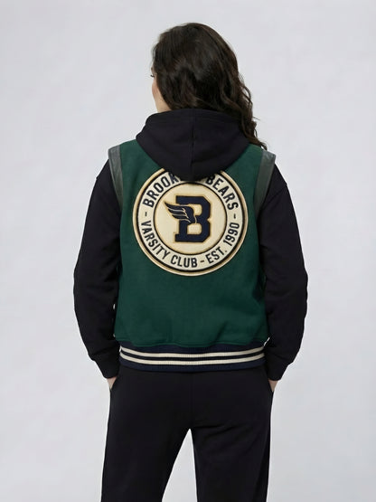 Person wearing a green and black varsity jacket with a logo on the back against a white background
