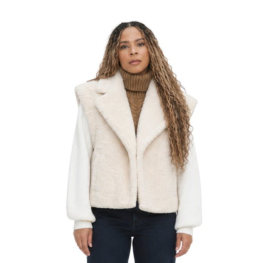 Woman wearing a white sherpa vest over a brown sweater on a white background