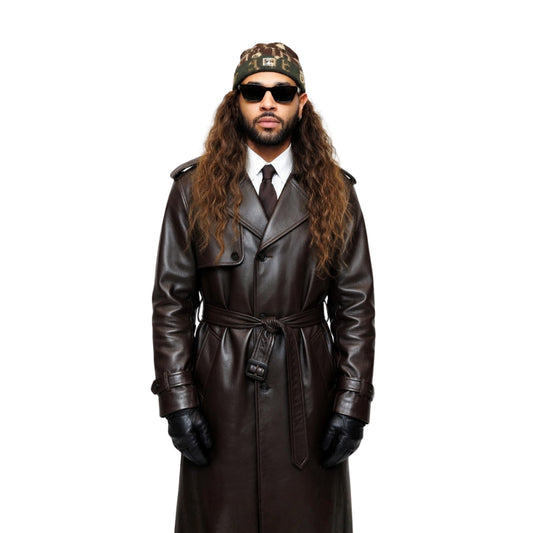 Man wearing a long brown leather coat, sunglasses, and a patterned cap on a white background