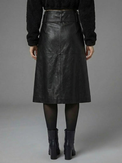 Person wearing a black leather skirt with a plain background