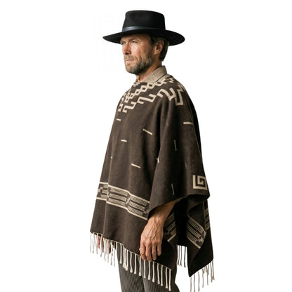 Man wearing a brown poncho with white patterns and fringes, and a black hat on a white background.