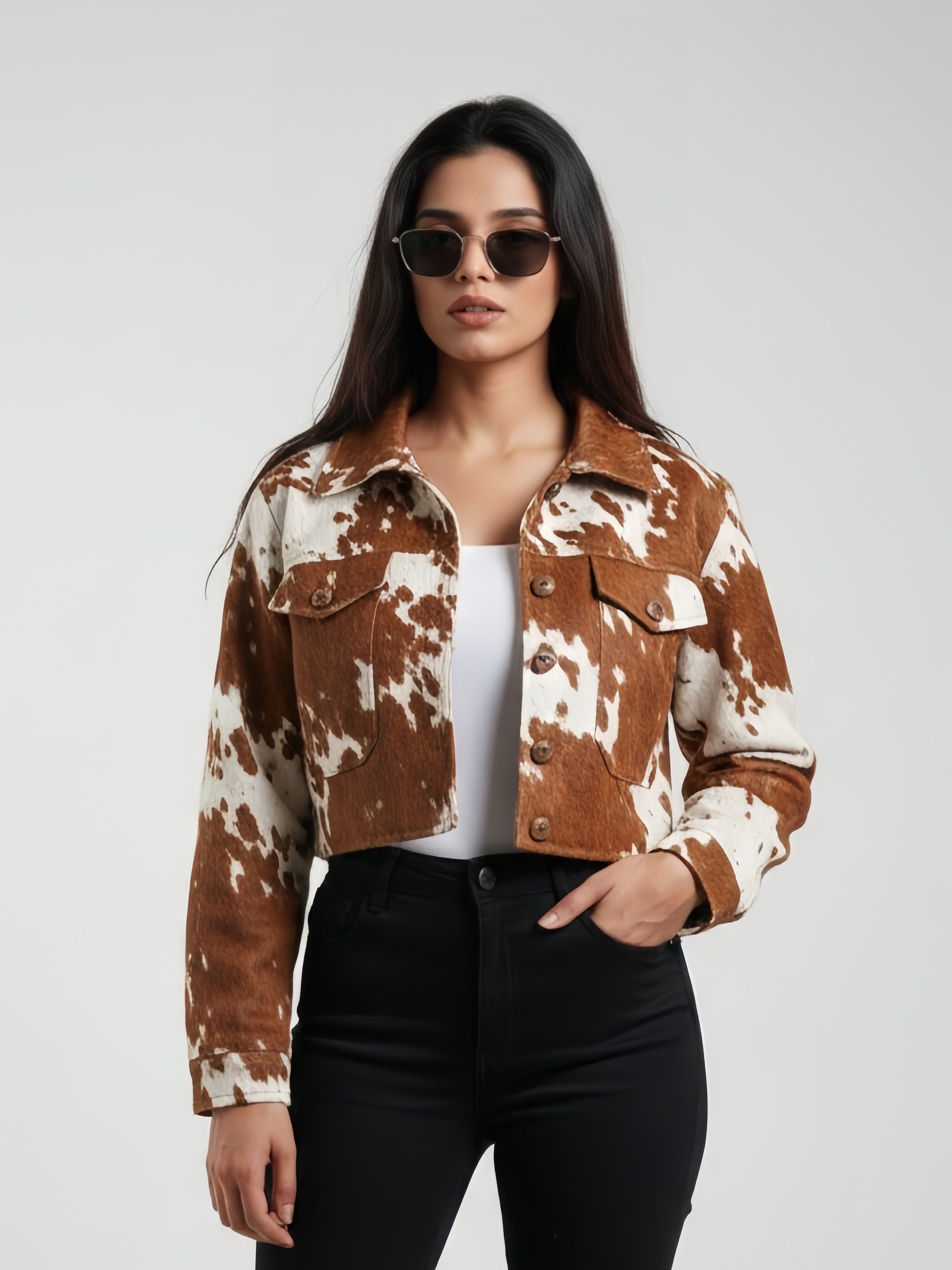 Woman wearing a brown and white cow print jacket on a plain background