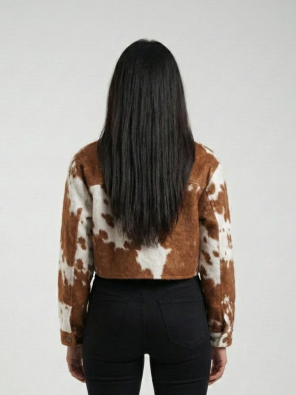 Person wearing a brown and white cow print jacket on a plain background