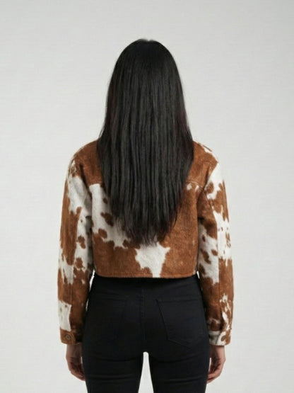 Person wearing a brown and white cow print jacket on a plain background