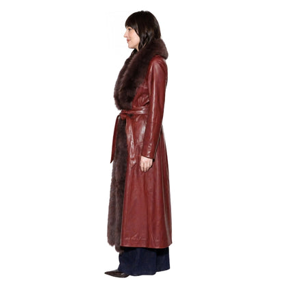 Woman wearing a long brown leather coat with fur collar on a white background