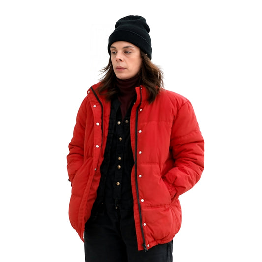Person wearing a red puffer jacket and black beanie on a white background