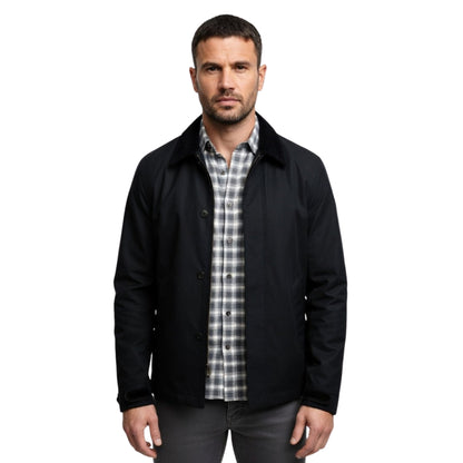Man wearing a black jacket over a plaid shirt on a white background