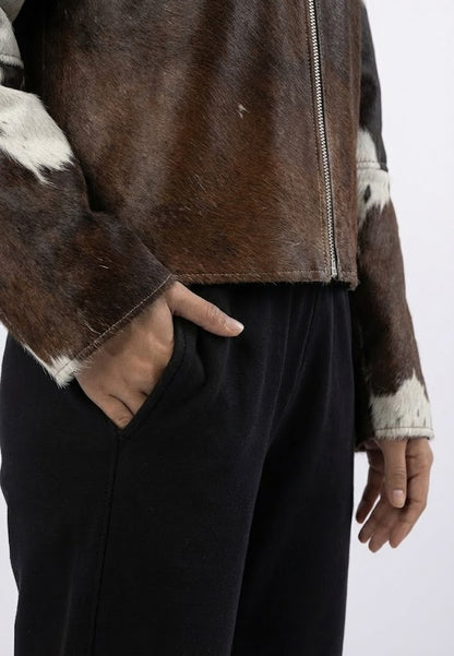 Person wearing a brown and white cowhide leather jacket on a white background