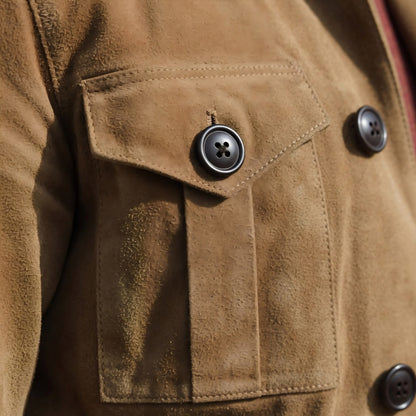 Close-up of a brown suede jacket with a button on a pocket