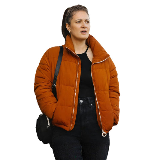 Woman wearing an orange quilted jacket on a white background