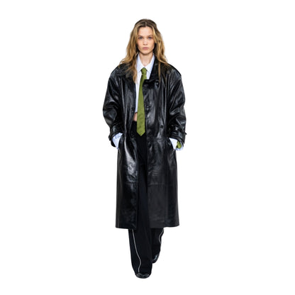 Person wearing a long black coat and green tie on a white background