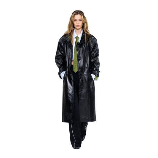 Person wearing a long black coat and green tie on a white background