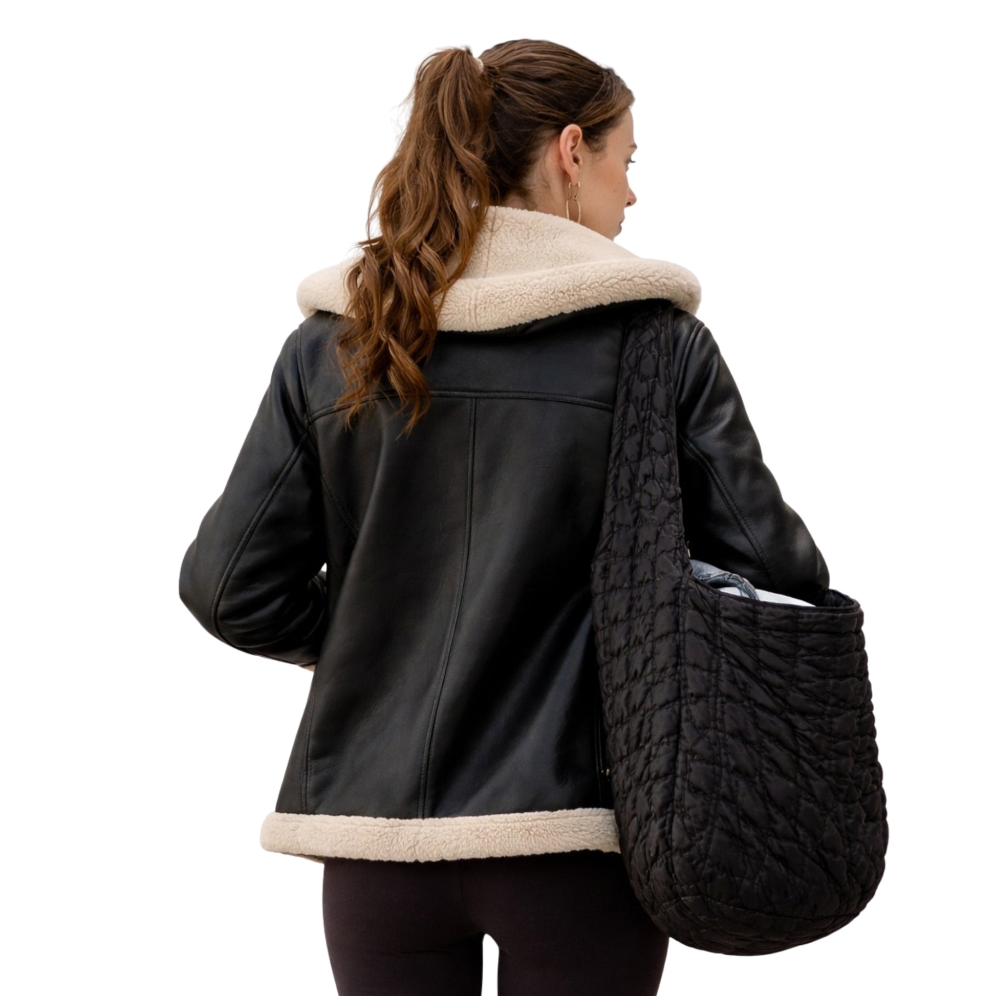 Woman wearing a black leather jacket with beige fur collar holding a textured black bag on a white background