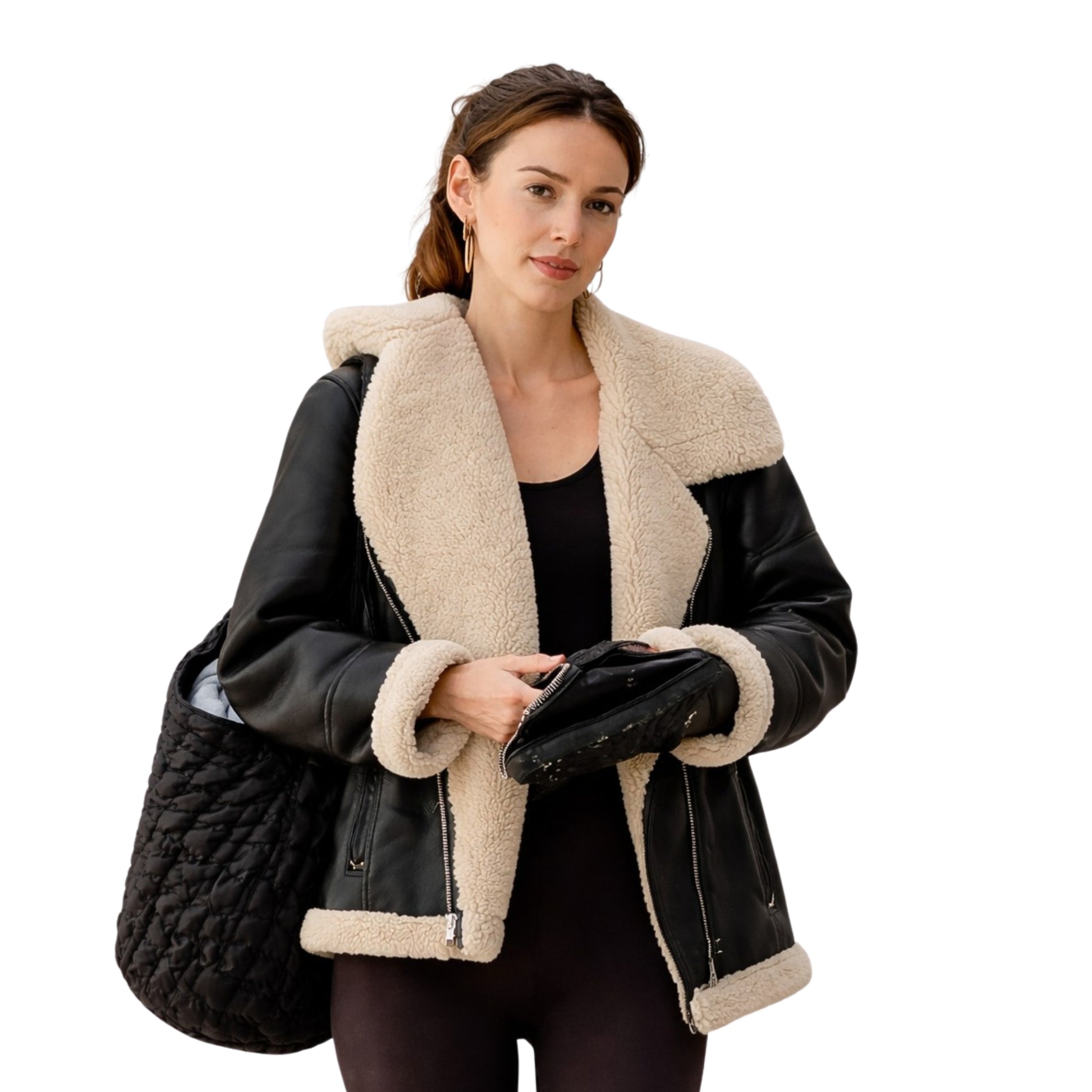Woman wearing a black leather jacket with beige shearling lining, holding a black quilted bag.