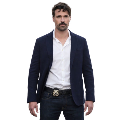 Man wearing a navy blazer, white shirt, and dark jeans on a white background