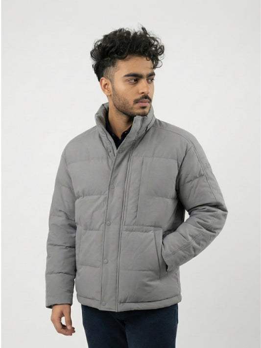 Man wearing a gray puffer jacket against a white background
