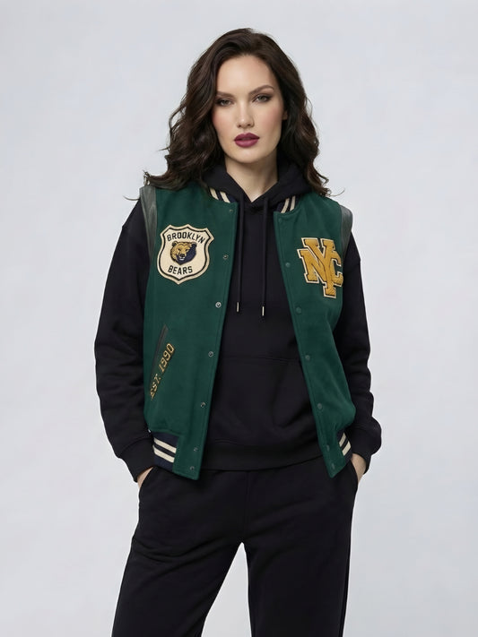 Woman wearing a green and black varsity jacket with logos on a light gray background