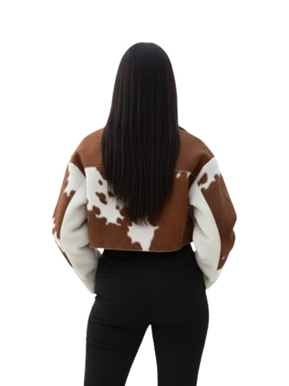 Person wearing a brown and white cow print jacket on a white background