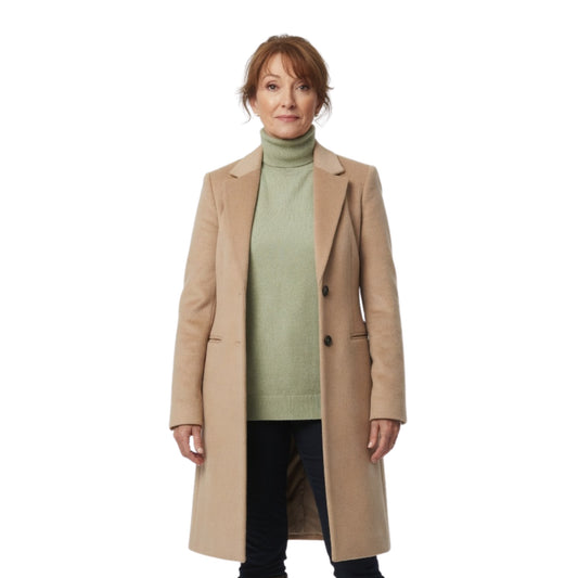 Woman wearing a beige coat over a green sweater on a white background