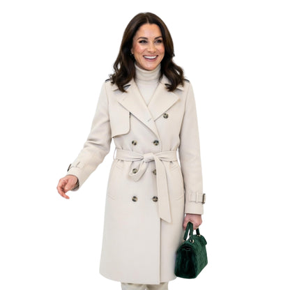 Woman wearing a beige trench coat holding a green handbag on a white background