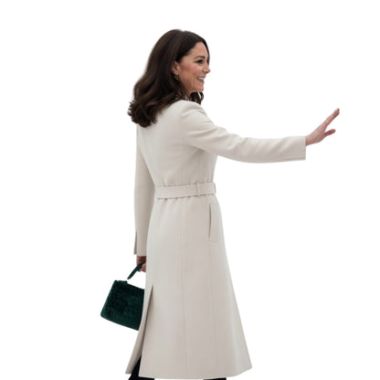 Woman in a beige coat holding a green handbag on a white background