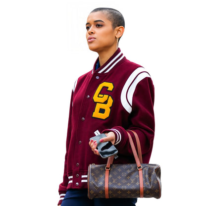 Person wearing a maroon letterman jacket with yellow initials, holding a Louis Vuitton bag.