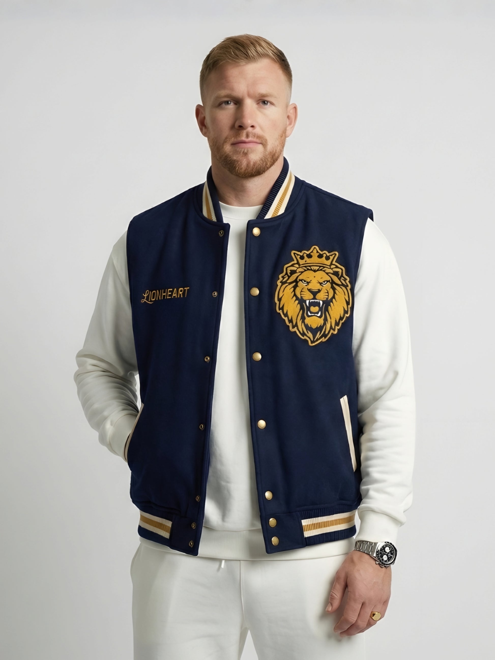 Man wearing a navy blue letterman jacket with a lion emblem on a white background