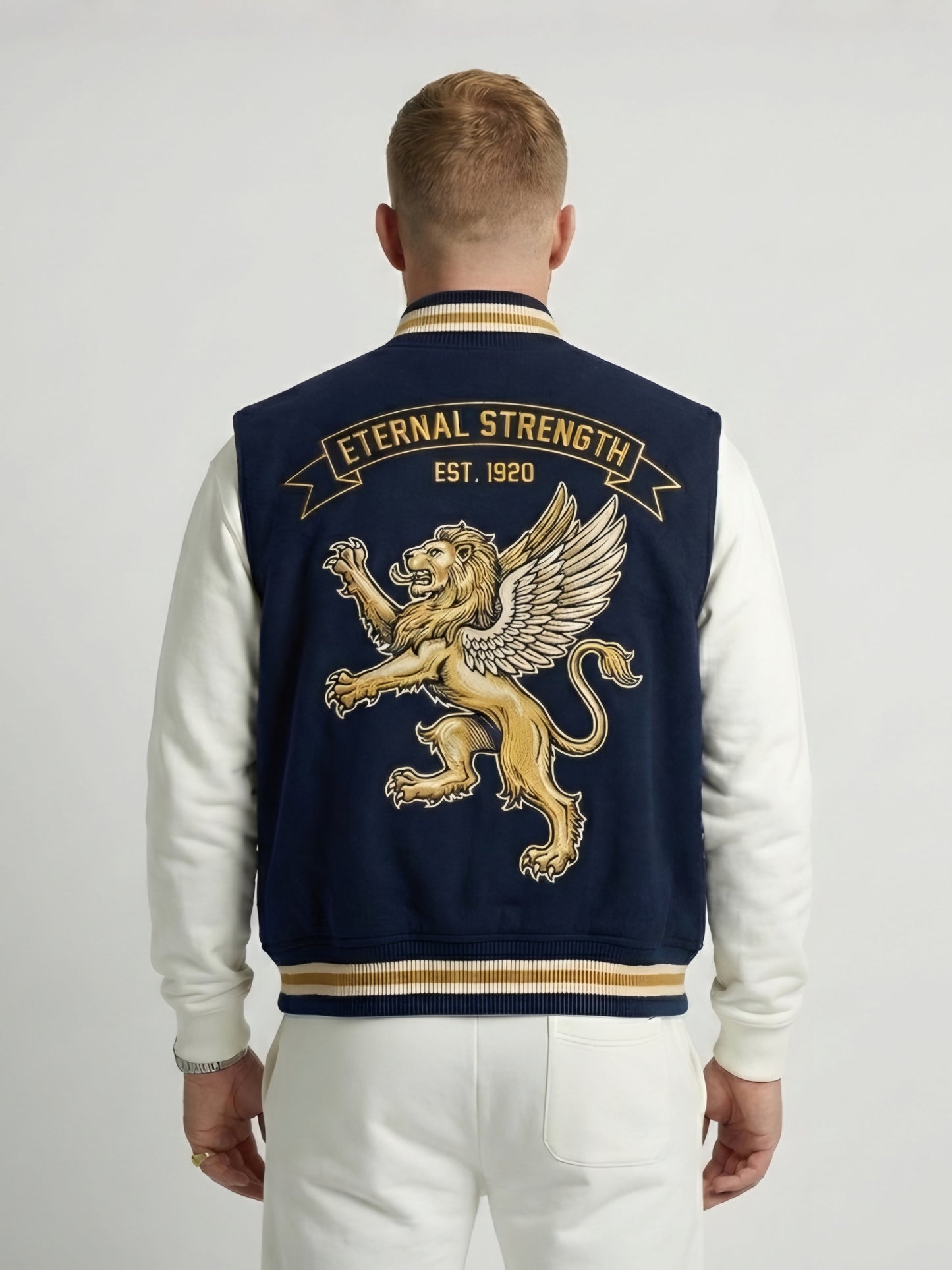 Man wearing a navy blue letterman jacket with gold lion emblem and 'Eternal Strength' text on the back.