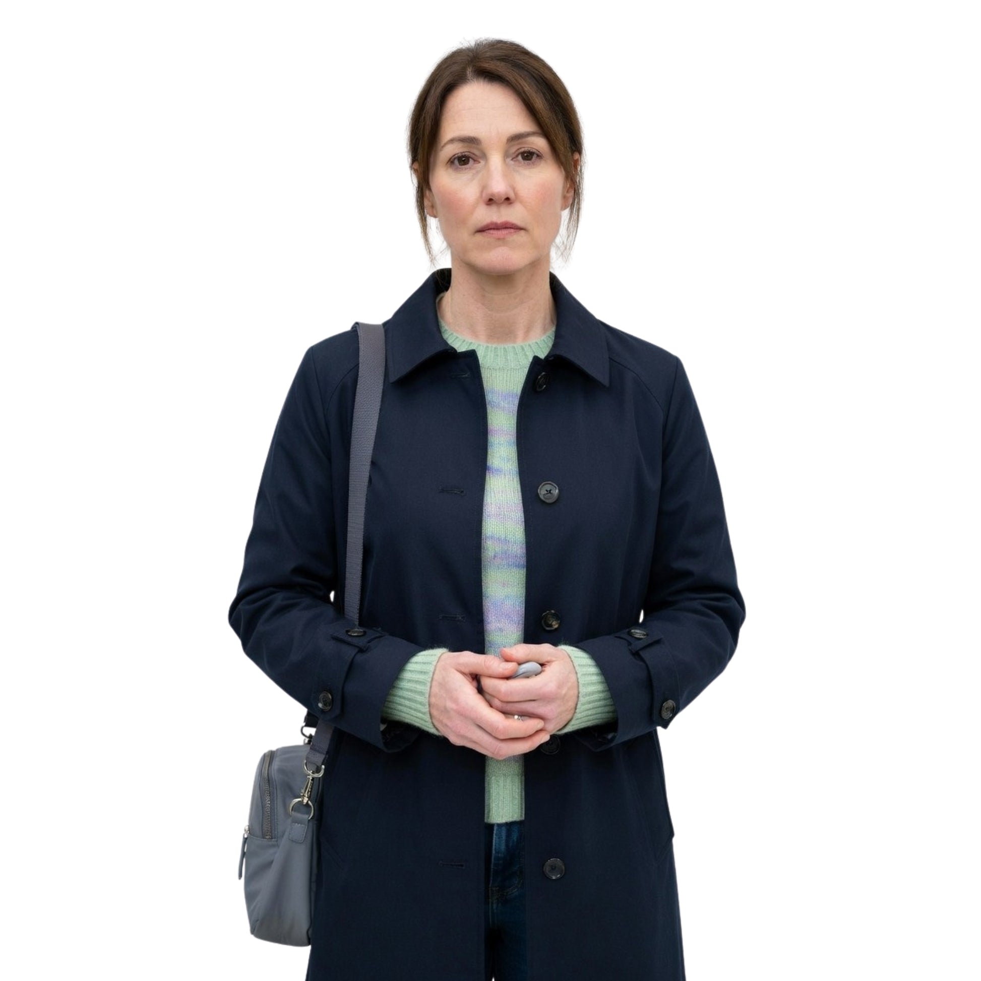 Woman wearing a navy coat and green sweater with a gray bag on a white background