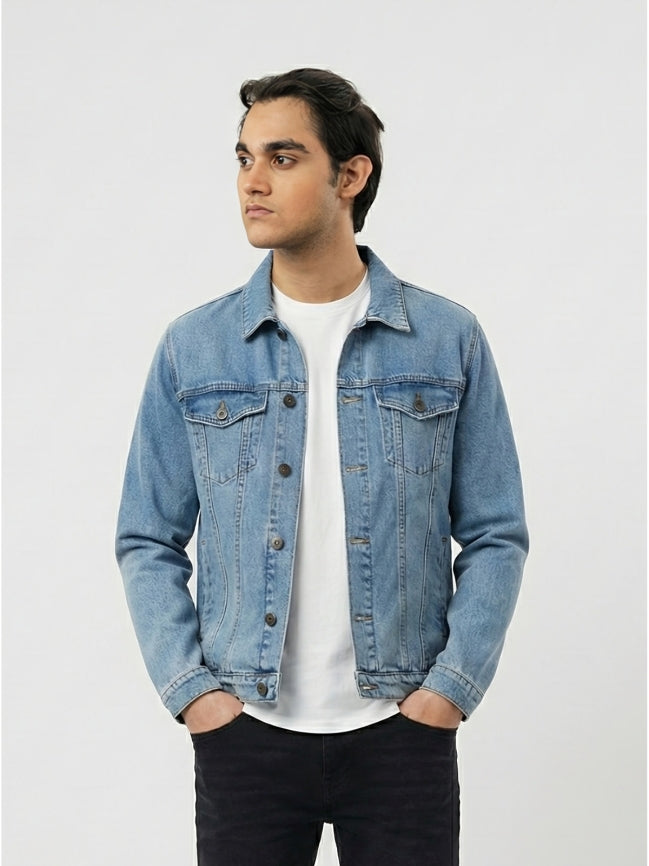 Man wearing a denim jacket over a white shirt on a light gray background