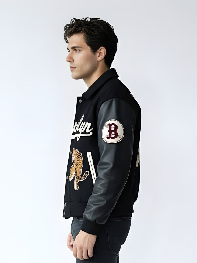 Man wearing a black varsity jacket with patches on a white background