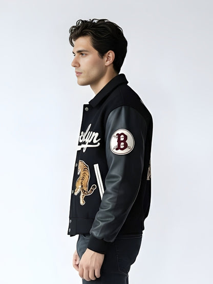 Man wearing a black varsity jacket with patches on a white background