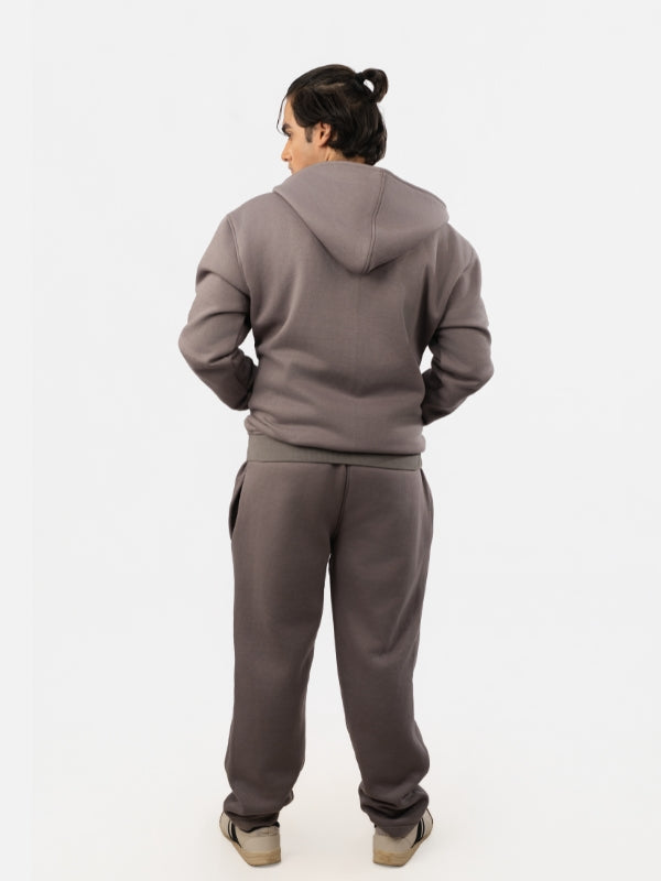 Person wearing a gray tracksuit on a white background