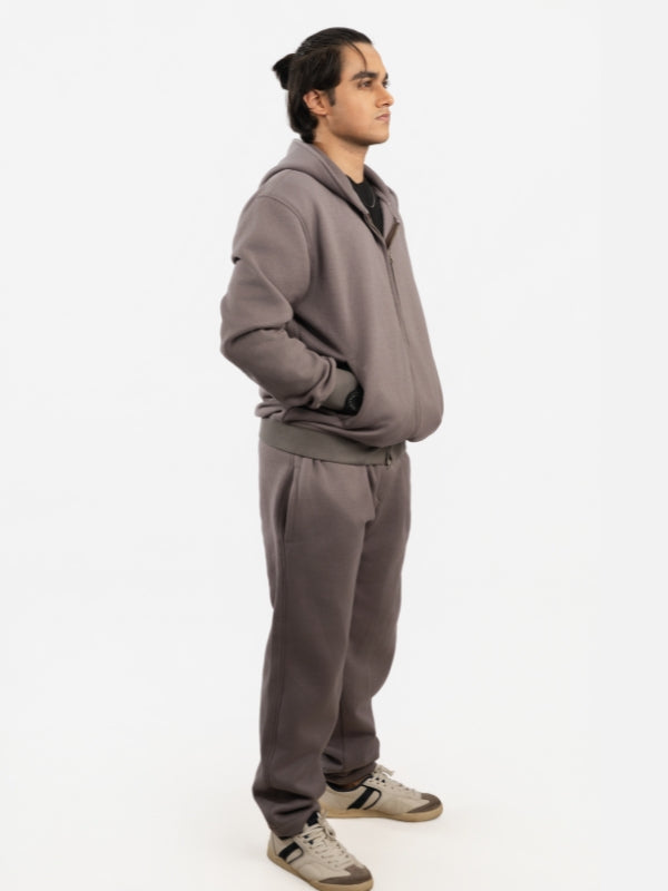 Person wearing a gray tracksuit on a white background