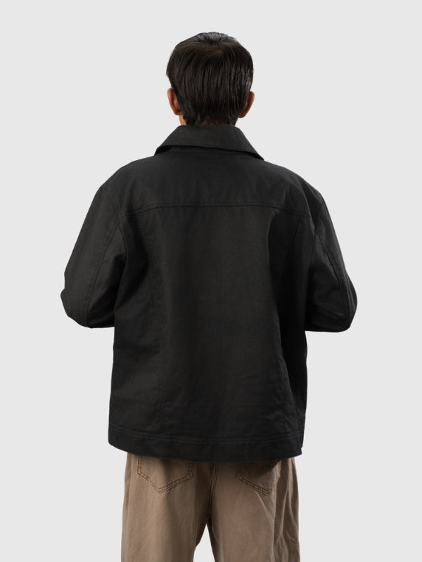 Person wearing a black jacket and beige pants on a white background