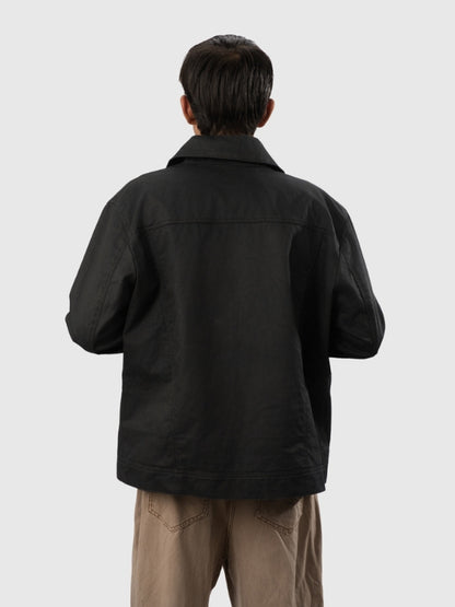 Person wearing a black jacket and beige pants on a white background