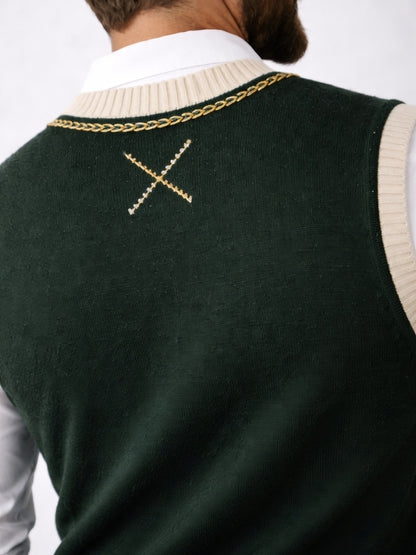 Green sweater vest with gold chain detail on a plain background