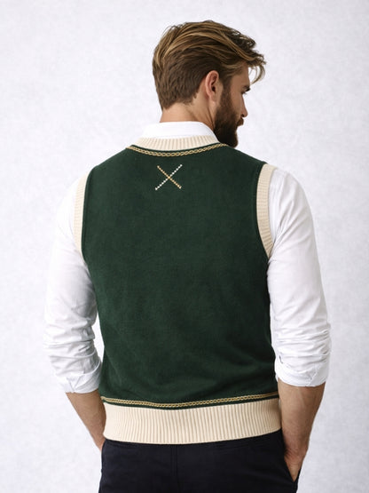 Man wearing a green sweater vest with a white shirt on a light gray background