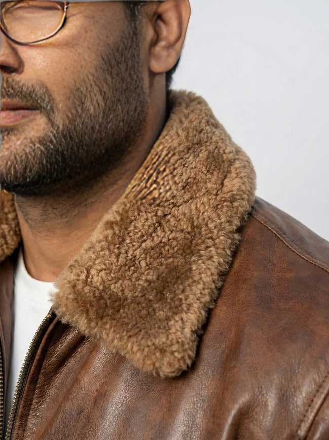 Close-up of a person wearing a brown leather jacket with a fur collar against a light gray background