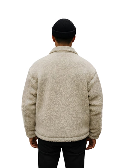 Person wearing a beige fleece jacket on a white background