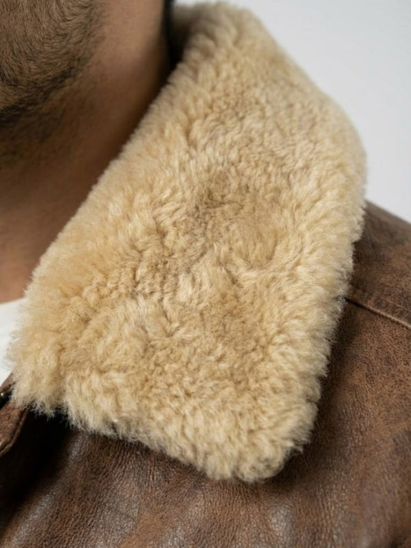 Close-up of a brown leather jacket with a fluffy beige fur collar.