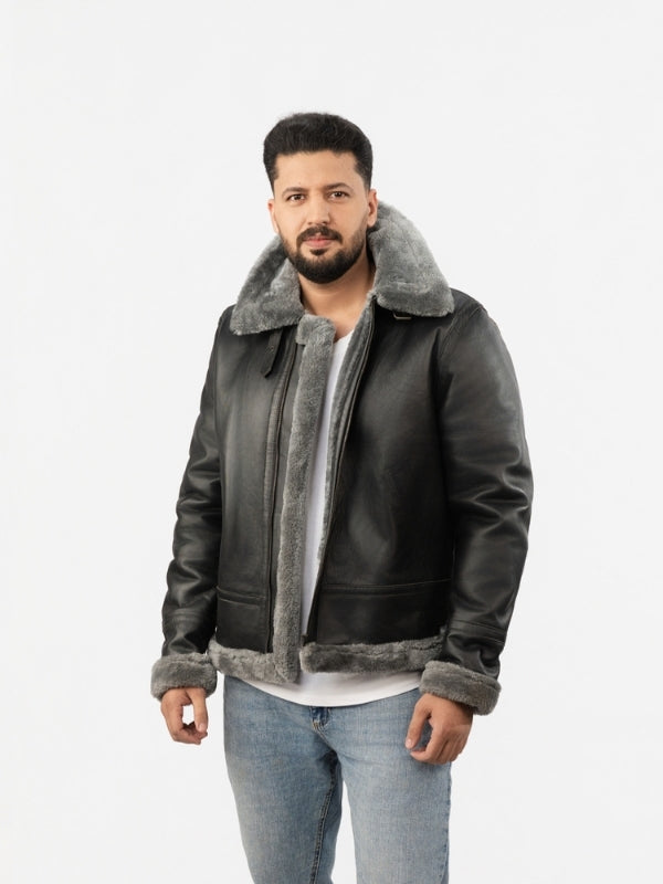Man wearing a dark leather jacket with gray shearling collar and cuffs on a white background