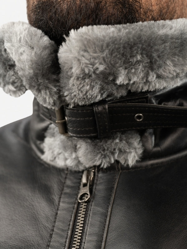 Close-up of a dark leather jacket with a fur-lined hood on a white background